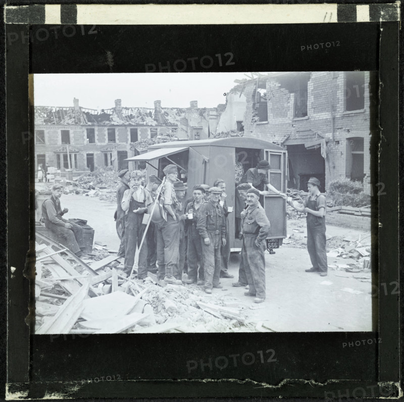 A group of men, possibly rescue workers, outside a tea van on a bomb damaged street, England, 1940-5 Creator: Norman Kingsley Harrison.