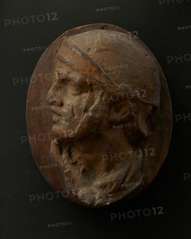 Cast of the head of Roman soldier in helmet and scarf with raised right arm. Creator: Unknown.