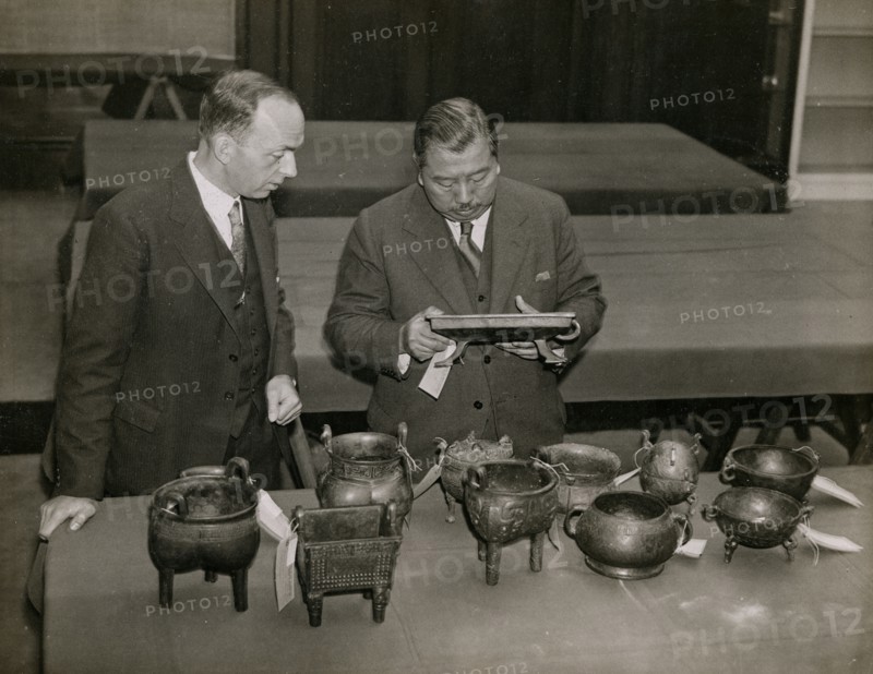 Zheng Tianxin (Dr F. T. Cheng) and Mr F.St. G. Spendlove examining exhibits, 1935. Creator: Topical Press Agency.