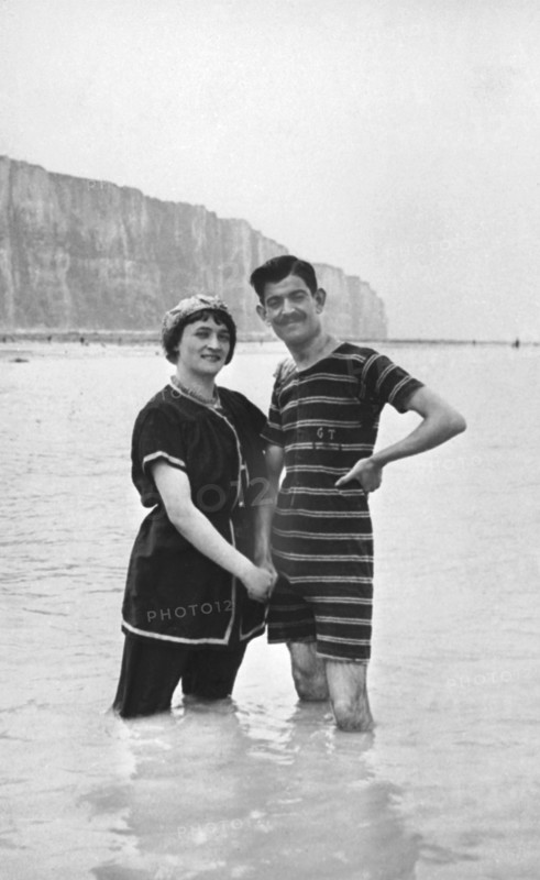 En 1908 à Etretat, couple prenant un bain de mer devant les falaises.