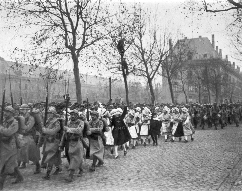 Défilé des troupes françaises à Metz auxquelles se mêlent des jeunes filles Lorraines enthousiastes après le 11 novembre 1918.