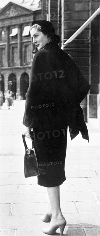Mode en 1951. Marque Schiaparelli Une élégante se promène vêtue d'une veste en lainage et d'une robe à buste en satin, assorti d'un sac à main et d'escarpins beige.
