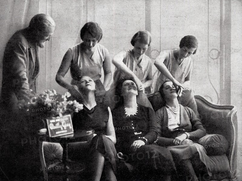 Mode et beauté à Paris en 1932. Une séance démonstrative de maquillage dans un salon de Dorothy Gray, 34 avenue George V, en présence du peintre Van Dongen, penché sur les jeunes femmes qui font la démonstration.