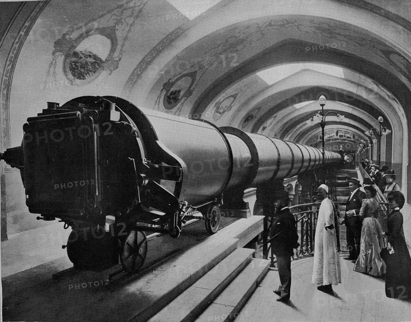 Exposition universelle de 1900 à Paris. La grande Lunette du Palais de l'Optique. Cette lunette colossale, le plus grande qui ait été construite jusqu'à ce jour, mesure 60 mètres de long sur 1 mètre 50 de diamètre, et pèse 20 000 kg. a l'une de ses extrémités, le Sidérostat de Foucault, animé d'un mouvement d'horlogerie, projette dans ce tube géant l'image de la lune.  Photographie parue dans "Le Panorama. L'Exposition universelle de 1900", publié sous la direction de René Baschet (Ludovic Baschet, éditeur).