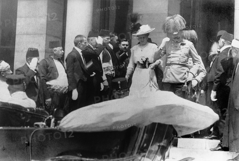 Le 28 juin 1914, lors d'une visite en Bosnie-Herzégovine, l'archiduc d'Autriche François-Ferdinand de HABSBOURG, héritier du trône austro-hongrois et neveu de François-Joseph, empereur d'Autriche-Hongrie et sa femme, la duchesse de Hohenberg, quittent l'Hôtel-de-Ville de Sarajevo pour monter dans leur voiture. Ils seront touchés peu de temps après par deux balles tirées par un serbe, Garilo PRINZIP. Dans la voiture qui les menait à l'Hôtel-de-Ville, le couple avait déjà évité une bombe lancée par un Serbe. Cet attentat précipita, par un jeu d'alliances, les nations européennes dans la Première Guerre mondiale.