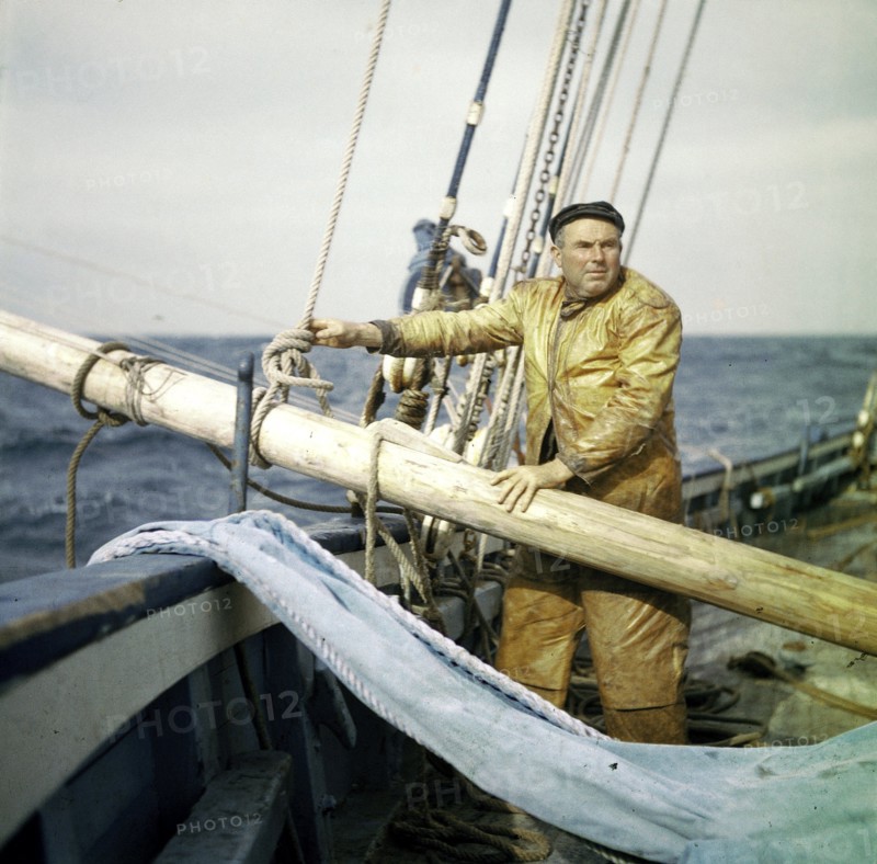 En août 1955, au large des côtes du Finistère, COLS, le patron du dernier thonier à voile de Concarneau, fait établir le spinneker (voile triangulaire d'avant) sur le tangon de pêche de tribord. Ce dernier, incliné par dessus la coque du bateau, porte sept lignes.
