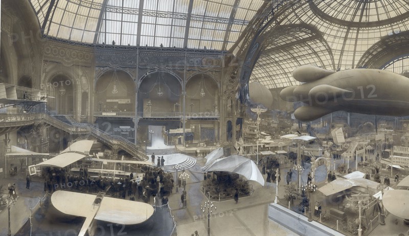 Pendant la première Exposition de l'Aéronautique au Grand Palais, du 24 au 30 décembre 1909, sous les verrières de la nef du Grand Palais:  de gauche à droite, en haut de l'escalier le "Farman"  au dessous le "Gastambide"  au premier plan, le "Blériot"  au deuxième plan, le "Wright"  au centre L'"Avion"  au fond, le "Delagrange"  suspendue, la "Demoiselle" de Santos-Dumont  et dessous le "Rep" (Esnault-Pelterie).  Photographie retouchée à l'encre de Chine et à la gouache, parue dans L'Illustration du 2 janvier 1909.