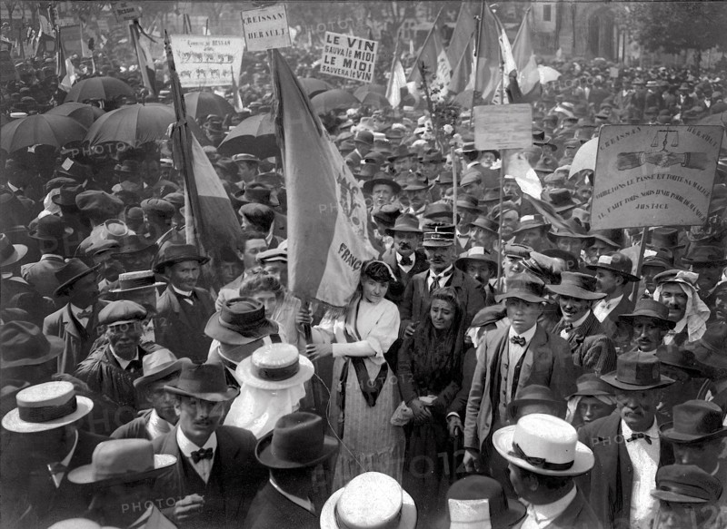 Meeting de Carcassonne, le dimanche 26 mai 1907, réunissant près de 250 000 vignerons.   "Ce fut en un décor pittoresque à souhait que se déroula, tambours battant, clairon sonnant, l'immense cortège des délégations venues de 100 kilomètres à la ronde. Multipliées, les pancartes aux inscriptions belliqueuses ou satiriques s'érigeaient en tête des groupes compacts."  Photographie et extrait d'article parus dans L'Illustration du 1er juin 1907.  Devant l'impuissance des pouvoirs publics à juguler la grave crise qu'ils  traversent (surproduction et effondrement du prix du vin depuis 1904), les viticulteurs du Midi, menés par Marcelin Albert, organisent des meetings dans les principales villes de la région pour crier leur misère et réclamer des mesures contre les fraudes de toutes sortes commises sur les vins.