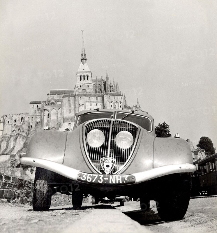Automobile en stationnement sur la digue du Mont-Saint-Michel.  Photographie parue dans L'Illustration du 2 octobre 1937.
