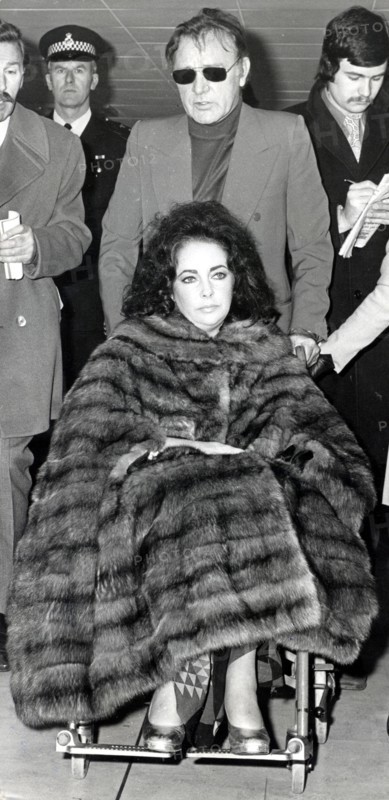 Elizabeth TAYLOR in a wheelchair with Richard BURTON, 1973