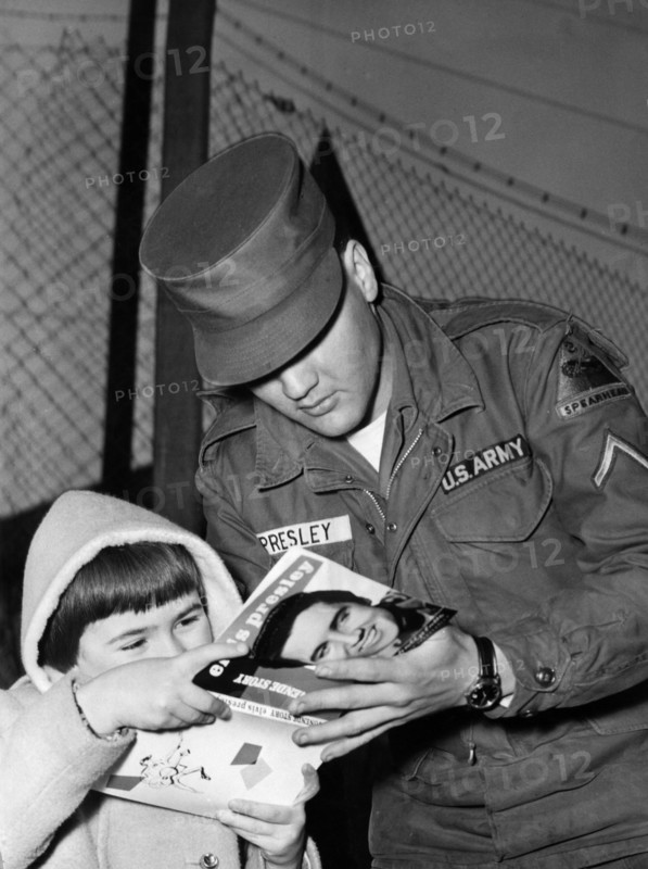 Elvis PRESLEY gives an autograph to a child in 1959