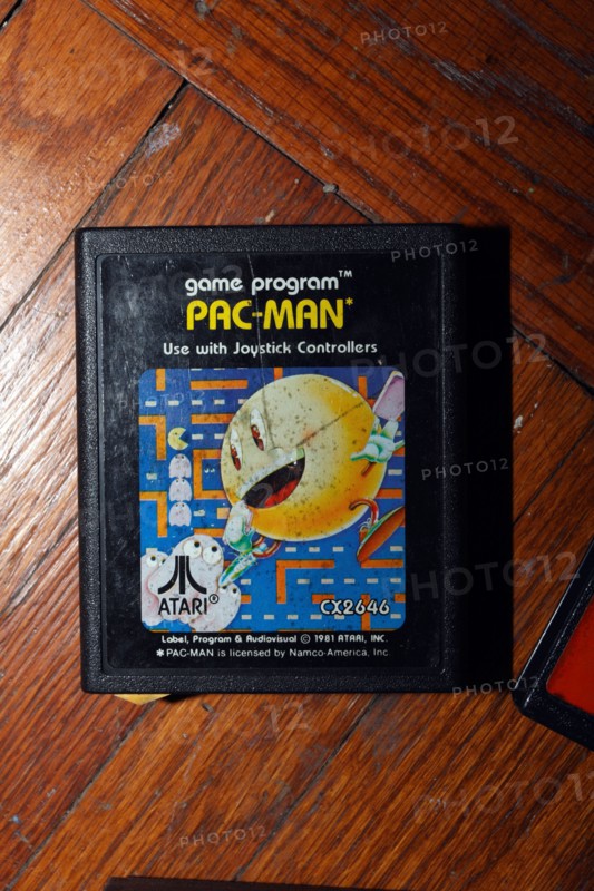 Pacman Atari video game cartridge on wood floor.