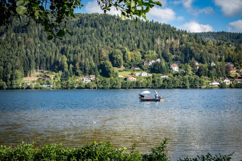 Man in fishing boat on a peaceful Lac de GÃ©rardmer, France, Europe
