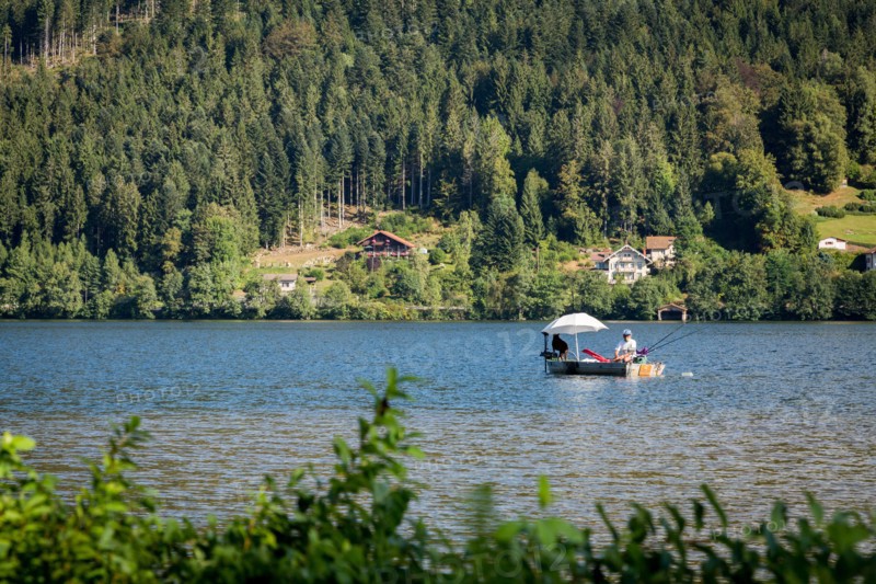 Man in fishing boat on a peaceful Lac de GÃ©rardmer, France, Europe