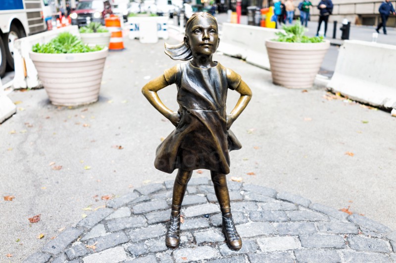 New York City, USA - October 30, 2017: Wall Street stock exchange The Fearless Girl statue facing Charging Bull metal in NYC Manhattan lower financial
