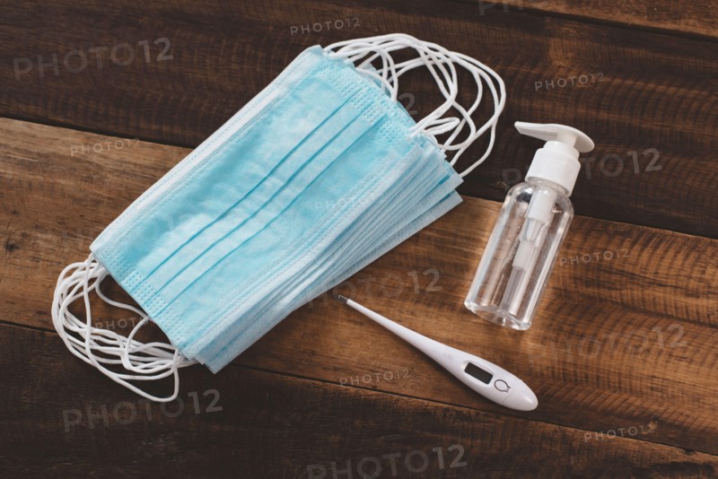 Hand Sanitizer, Surgical Mask and Digital Thermometer on a wooden table. Concept of pandemic, Pollution and health care