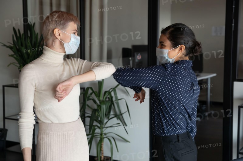 Female colleagues greeting in office touching elbows