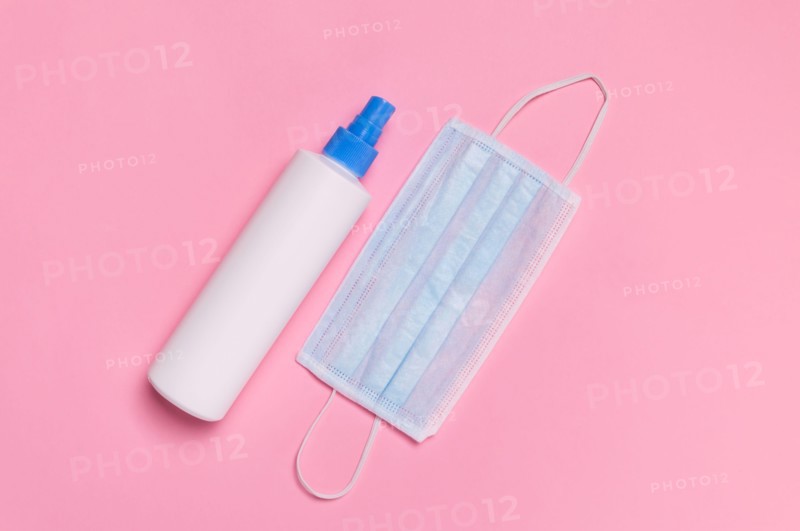 Coronavirus protection. Medical surgical mask and disinfectant or hand sanitizer on pink background. Hygiene measures to prevent spread of Covid-19 pa