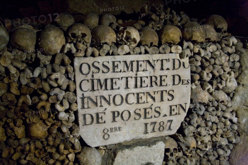 Human skulls and bones stacked in rows in the underground Catacombs, Paris, France.