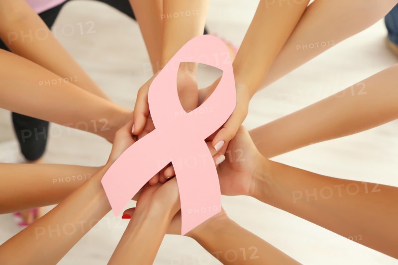 Women hands joined in circle holding breast cancer symbol
