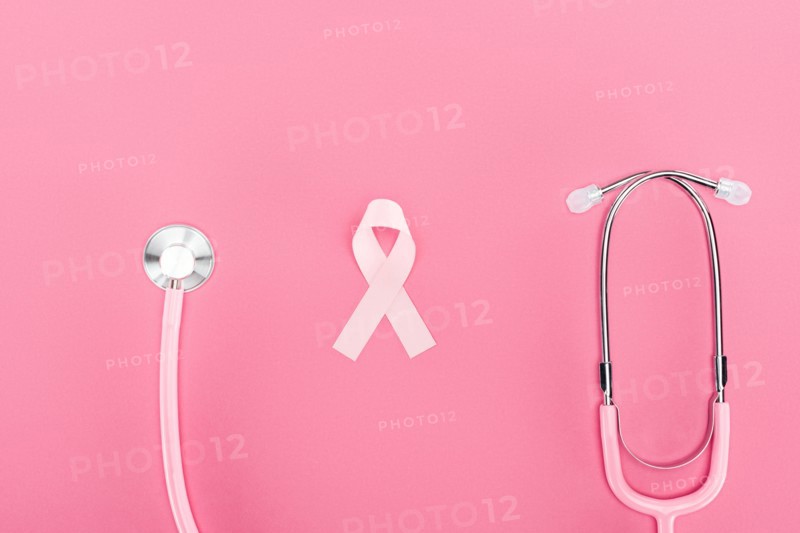 top view of stethoscope and pink breast cancer symbol on pink background
