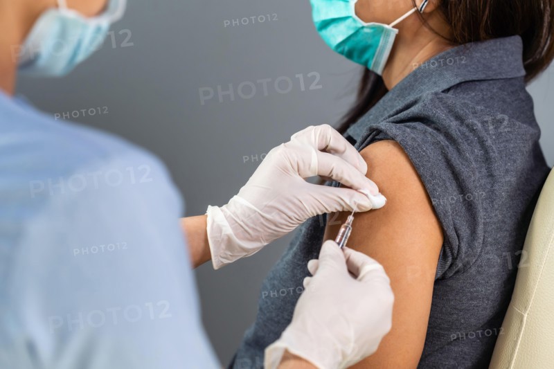 close up doctor holding syringe and using cotton before make injection to patient in medical mask. Covid-19 or coronavirus vaccine