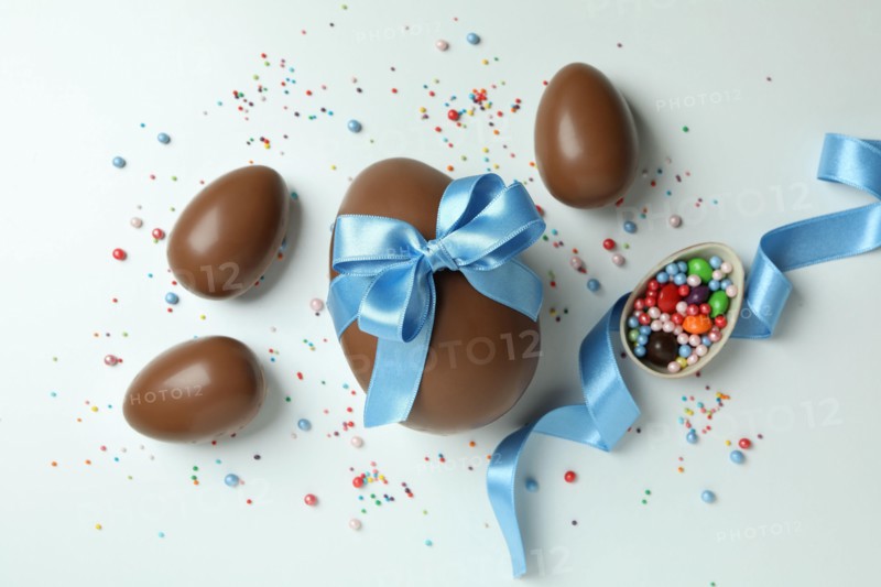 Easter chocolate eggs, candies and sprinkles on white background