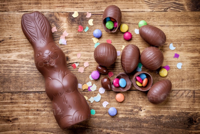 Delicious chocolate easter eggs and sweets on wooden background