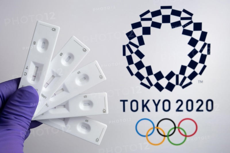 Negative PCR tests in front and blurred Tokyo 2020 logo on the blurred background. Concept for Tokyo COVID Olympic games in 2021. Stafford, United Kin
