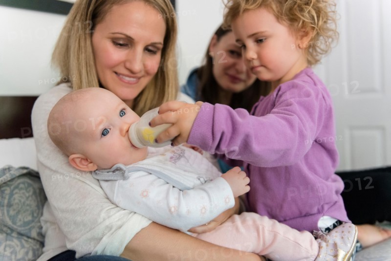 Caucasian girl feeding bottle to baby sister