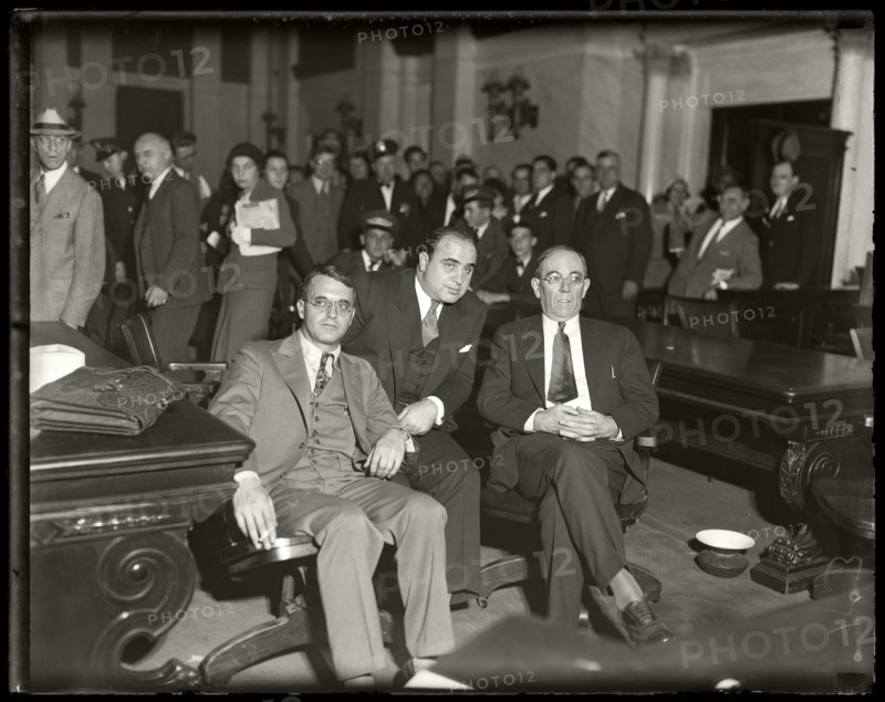 Al Capone sits in federal court during his tax evasion trial with his attorneys Michael Ahern, left, and Albert Fink, right. Chicago, Illinois,  October 7, 1931. Image from 4x5 inch glass negative.