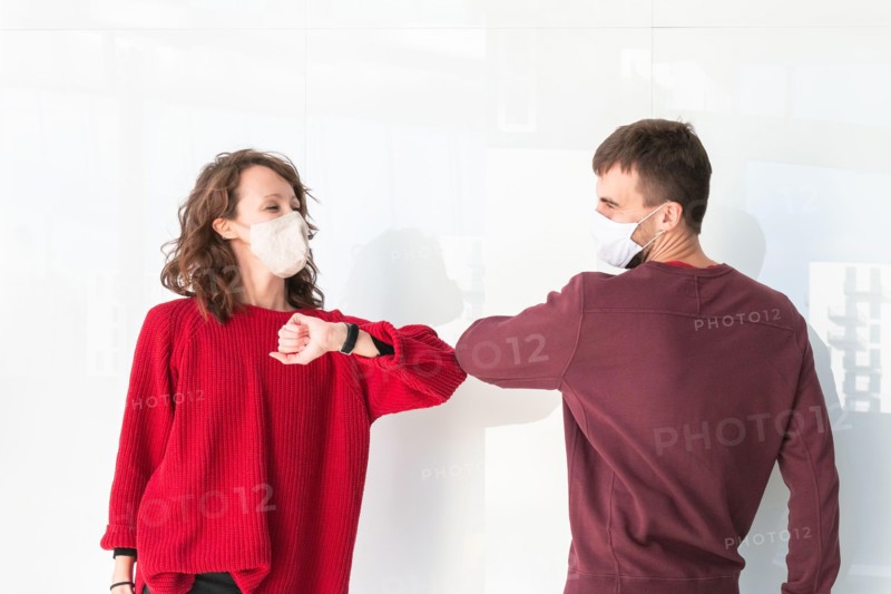Two people greet elbow bump. Greeting with elbow bump in street. Colleagues are doing elbow bumps in office. New style of greeting during coronavirus.