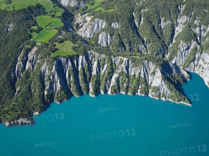 AERIAL VIEW - Landscape of eroded ravines on the lakeshore of Lake Serre-Poncon. La Bréole, Alpes de Haute-Provence, France.