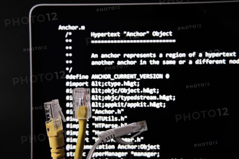 Internet cable and World Wide Web source code which was sold as NFT by Tim Berners Lee seen on the blurred background screen. Concept. Stafford, UK, J
