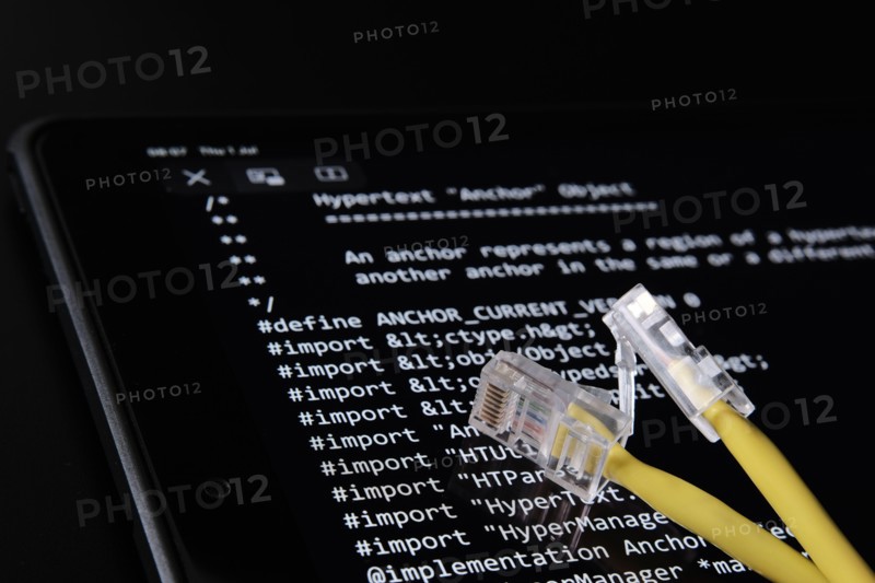 Internet cable and World Wide Web source code which was sold as NFT by Tim Berners Lee seen on the blurred background screen. Concept. Stafford, UK, J