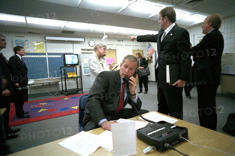 As Dan Bartlett, Deputy Assistant to the President, points to news footage of the World Trade Center Tuesday, Sept. 11, 2001, President George W. Bush gathers information about the terrorist attack from a classroom at Emma E. Booker Elementary School in Sarasota, Fla. Also pictured from left are: Deborah Loewer, Director of White House Situation Room, and Senior Adviser Karl Rove. Photo by Eric Draper, Courtesy of the George W. Bush Presidential Library