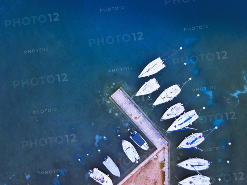aerial view of boats parked near pier on the lake, blue water landscape from drone