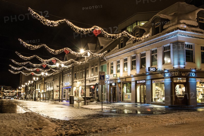A view of the central street of Tromsø, Storgata, at polar night in winter, all lit up, with decorations for Christmas.