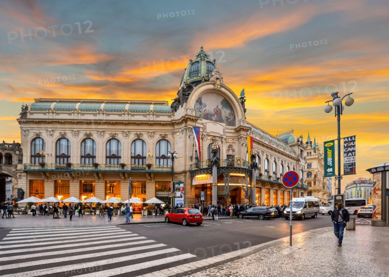 Sun sets in New Town Prague, Czech Republic as locals traverse the main street in front of the Prague Municipal House.