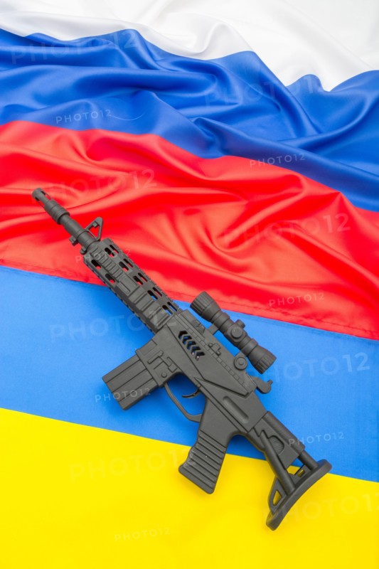 Russian and Ukrainian flags with black painted toy assault rifle. For Ukraine-Russia crisis, Russian invasion, tensions and war in Ukraine.