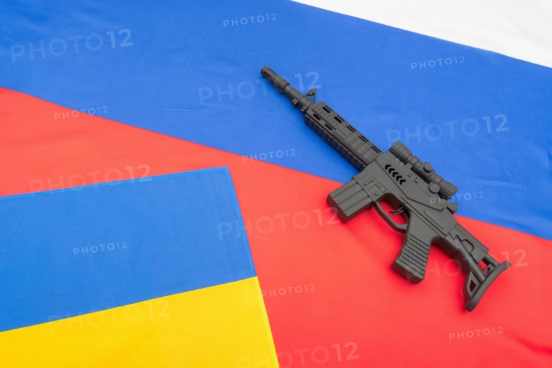 Russian and Ukrainian flags with black painted toy assault rifle. For Ukraine-Russia crisis, Russia Ukraine invasion, tensions / war in Ukraine.