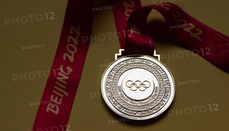 January 14, 2022, Beijing, China. Gold medal of the XXIV Olympic Winter Games on a yellow background.