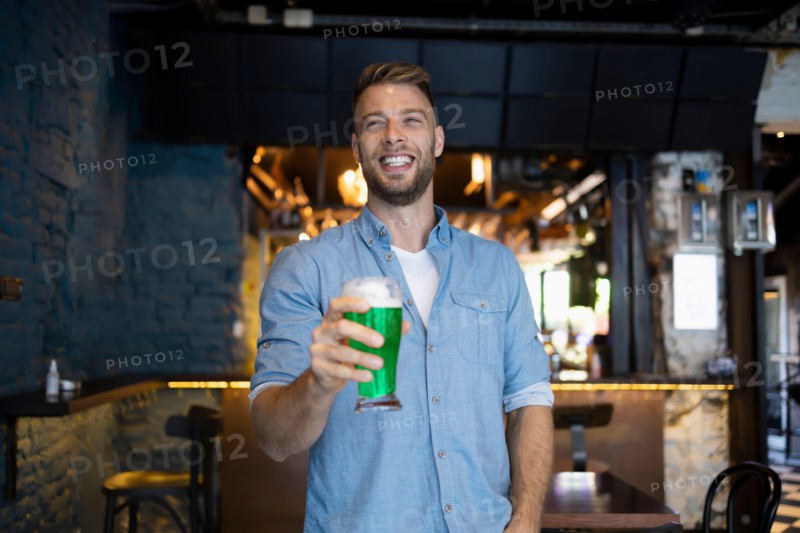 Handsome man holding a beer in a pub for St. Patrick's Day