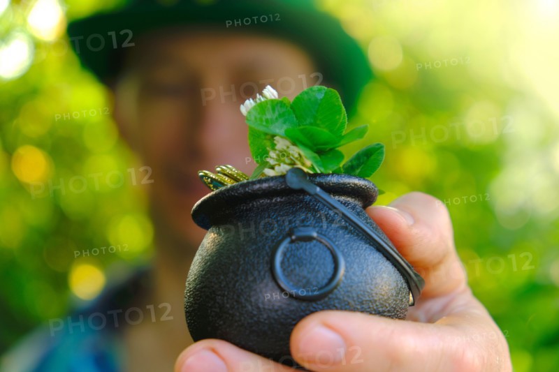 Saint Patrick .clover leaf in bowler hat with gold coins in the hand of a man .Four-leaf clover. Good luck symbol.Irish traditional spring holiday