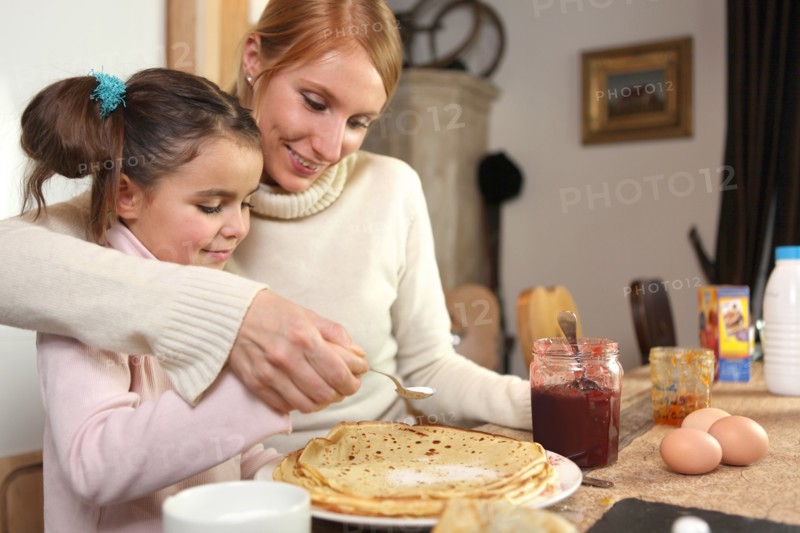 loving mother making crepes with little girl
