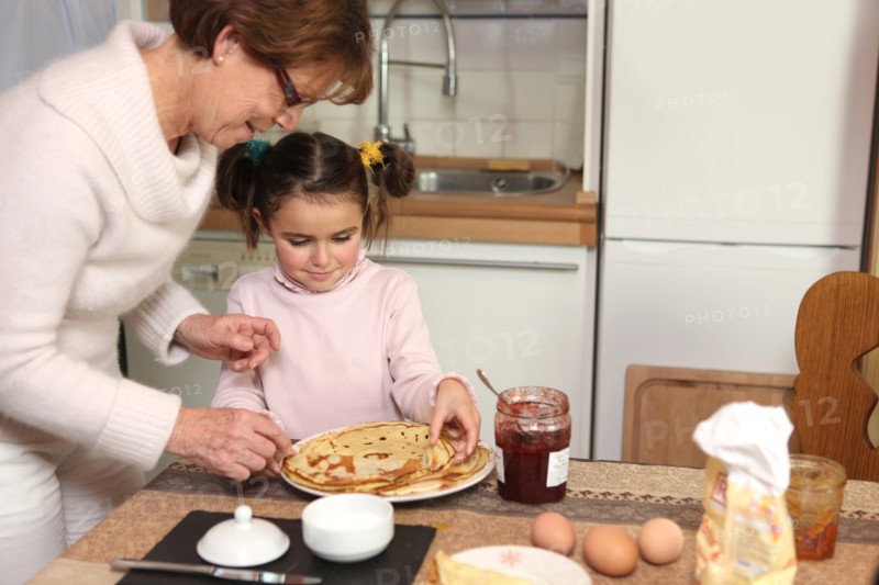 mother preparing crepes with little girl