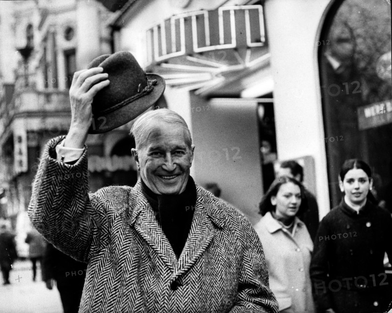Actor Maurice Chevalier tips his hat on his walk