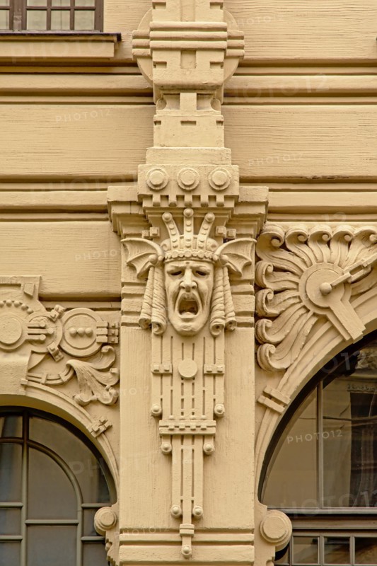 Art deco decoratio with a screaming crowned man`s head abstract flowers, found on the facade of a Jugendstil building in riga, Latvia