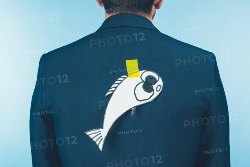 back view of businessman in suit with paper made fish on back, april fools day concept