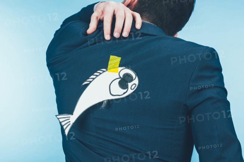 back view of businessman in suit with paper made fish on back, april fools day concept